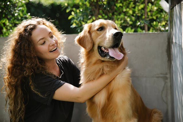 Person smiling while petting a dog outside